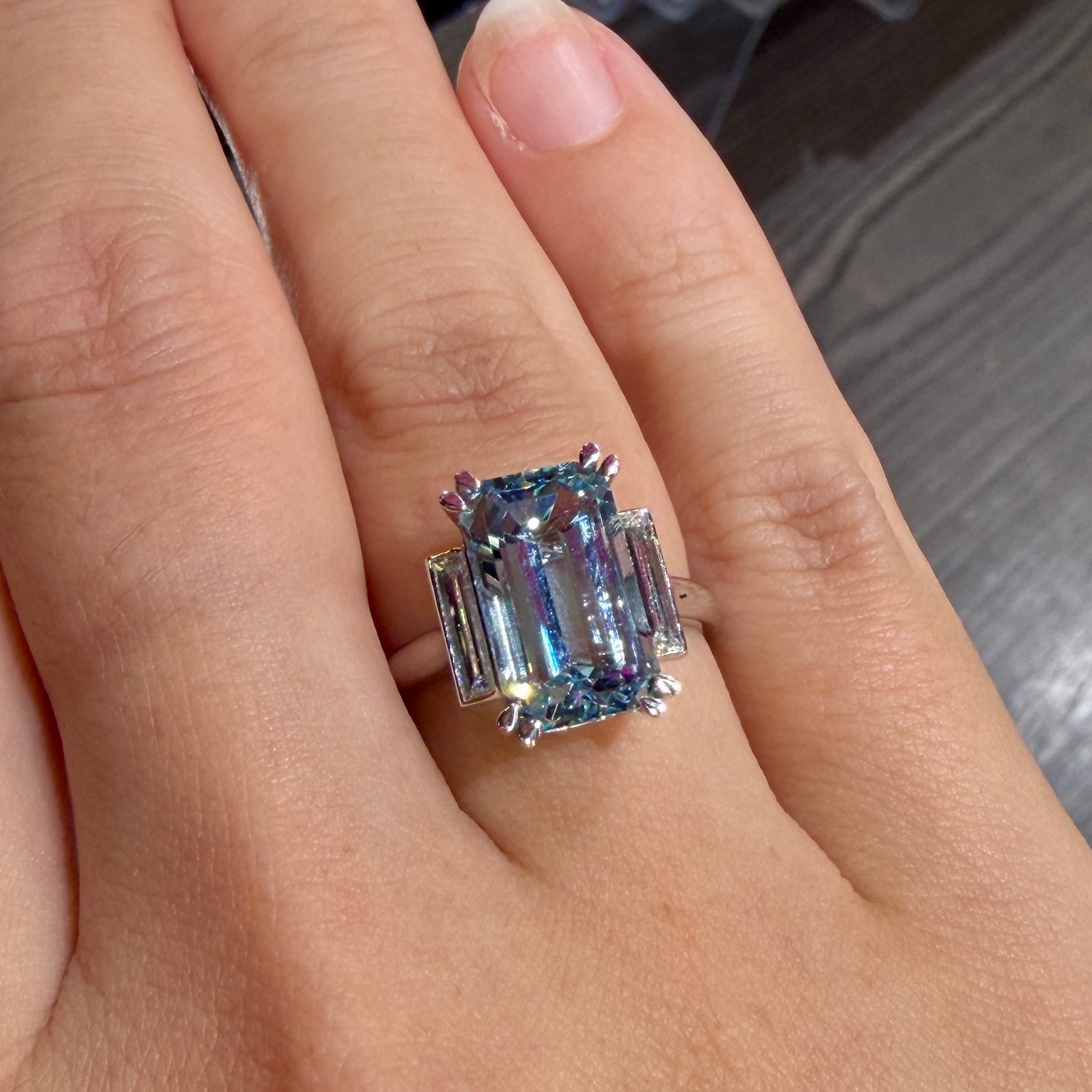 Aquamarine and dimaond ring featuring emerald cut aquamarine stone and elongagted baguette diamonds on hand