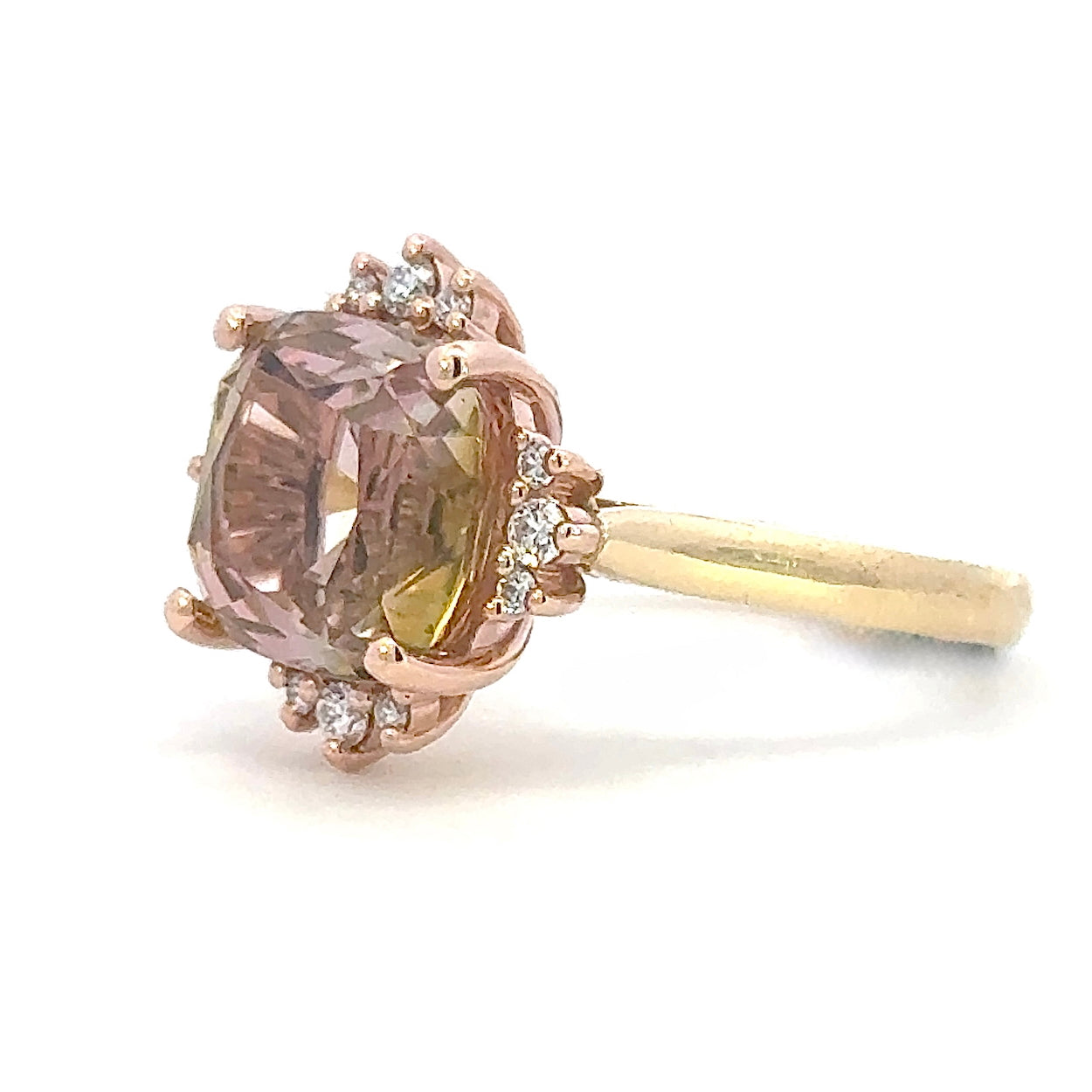 Rose and yellow gold ring with a large brown gold tourmaline gemstone and smaller diamonds on a white background