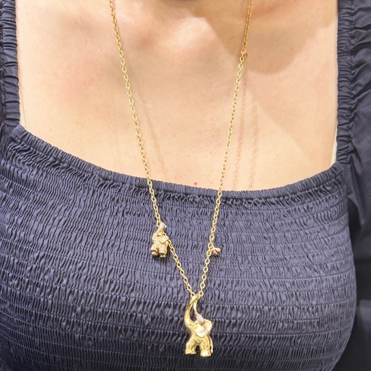 ole lynggaard 90cm 18ct yellow Gold necklace with elephant pendants worn by a person in a dark top. twisted anchor link